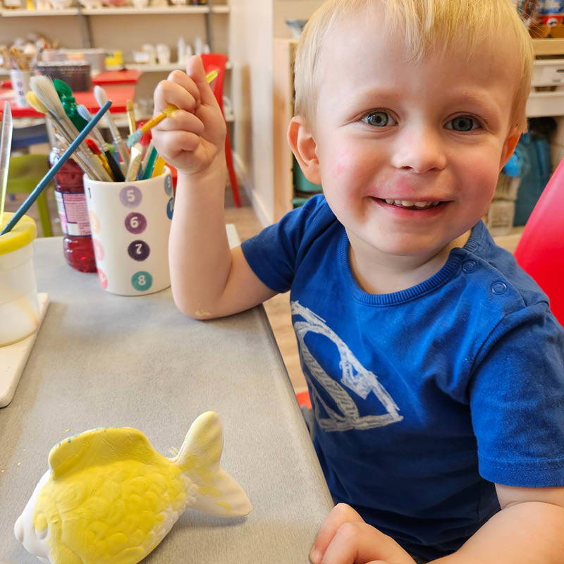 Child painting unglazed pottery at Paint A Pot Place Bourne